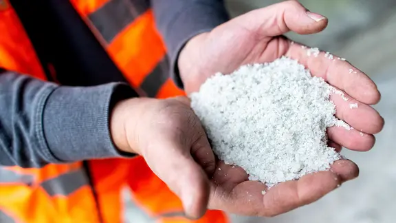 Ein Mitarbeiter der Stadt Hildesheim hält Streusalz in den Händen.