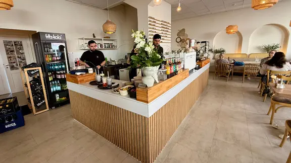 Ein Café-Innenraum mit großem Tresen in der Mitte und zwei Mitarbeitern dahinter | NDR Ein Café-Innenraum mit großem Tresen in der Mitte und zwei Mitarbeitern dahinter