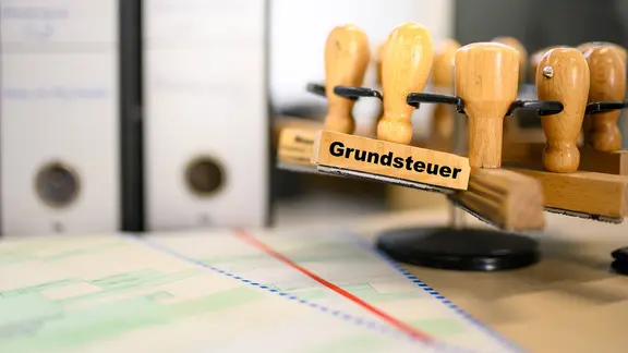 Ein Stempel mit der Aufschrift "Grundsteuer" auf einem Schreibtisch. | IMAGO / Lobeca Ein Stempel mit der Aufschrift "Grundsteuer" auf einem Schreibtisch.