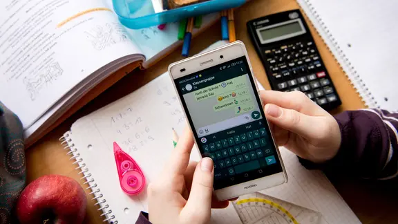 Eine Schülerin sitzt mit ihrem Handy und ihren Schulsachen an einem Schreibtisch. | Sven Hoppe Eine Schülerin sitzt mit ihrem Handy und ihren Schulsachen an einem Schreibtisch.