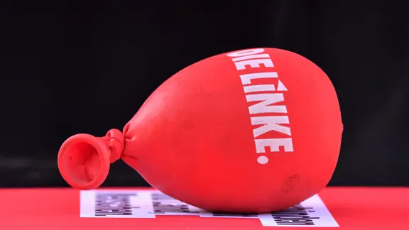 Ein mit Sand gefüllter Luftballon mit dem Aufdruck "Die Linke" liegt auf einem Tisch.