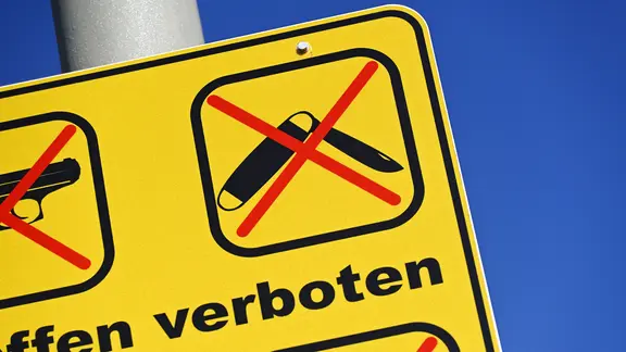 Waffenverbotsschild mit durchgestrichenem Messersymbol. | picture alliance/CHROMORANGE/Christian Ohde, Christian Ohde Waffenverbotsschild mit durchgestrichenem Messersymbol.