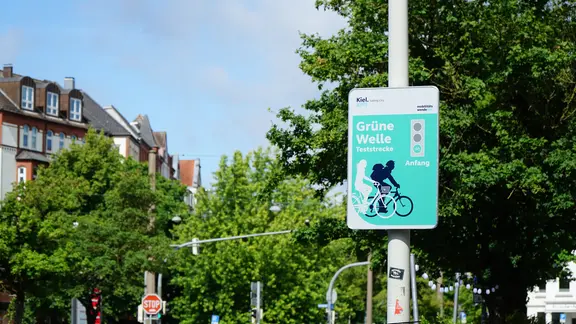 Diese grünen Schilder markieren Anfang und Ende der 500 Meter langen Strecke in der Olshausenstraße. | NDR, Moritz Mayer Ein grünes Schild gibt eines Teststrecke für eine grüne Welle für Fahrradfahrer bekannt.