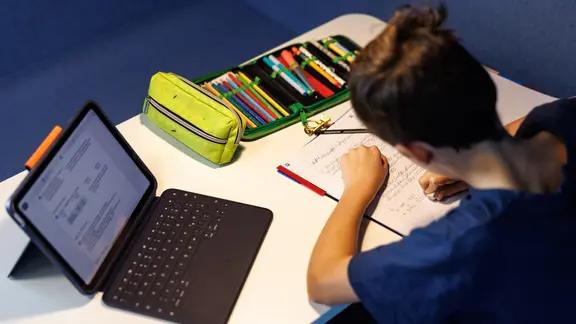 Ein Schüler einer fünften Klasse macht sich Notizen, während neben ihm ein Tablet zu sehen ist. | dpa, Matthias Balk Ein Schüler einer fünften Klasse macht sich Notizen, während neben ihm ein Tablet zu sehen ist.