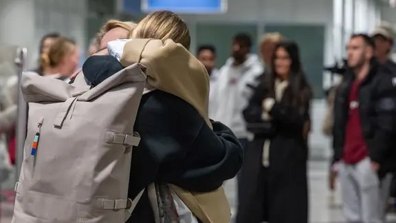 Menschen umarmen sich auf dem Flughafen München. | picture alliance / dpa, Armin Weigel Menschen umarmen sich auf dem Flughafen München.