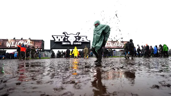 Jemand springt auf dem Festivalgelände des Wacken Open Airs in den Matsch.
