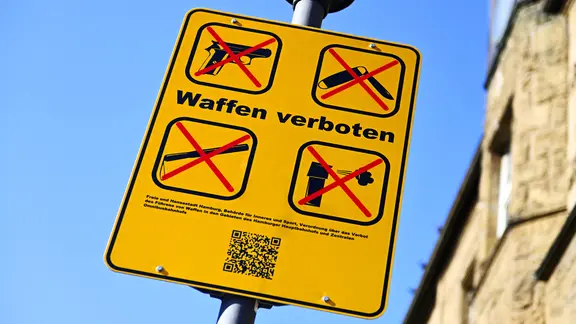 Auf einem Hinweis·schild steht: Waffen verboten. | picture alliance / CHROMORANGE, Christian Ohde Auf einem Hinweis·schild steht: Waffen verboten.