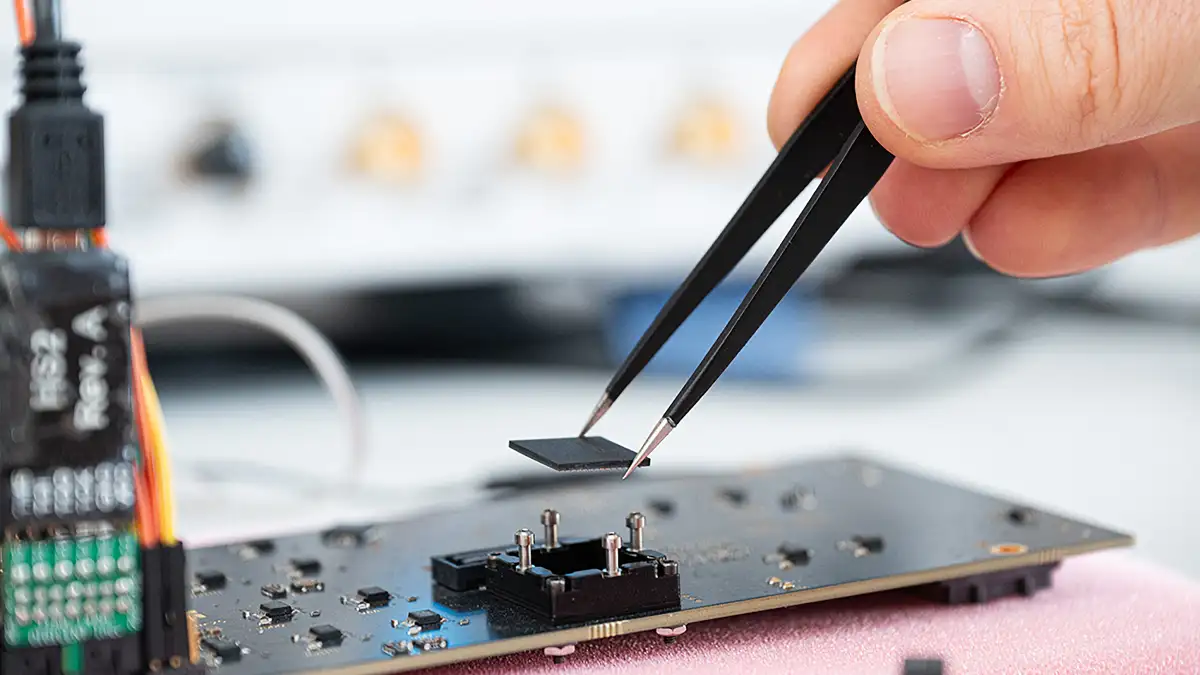 Ein Forscher setzt einen "Masur"-Chip auf einer Test-Leiterplatte ein. Foto: Rafael Vinz für das Barkhausen-Institut