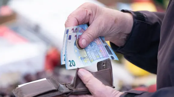 Eine Frau sortiert Wechselgeld für ihre Einkäufe in ein Portemonnaie. | Sebastian Kahnert/dpa Eine Frau sortiert Wechselgeld für ihre Einkäufe in ein Portemonnaie.