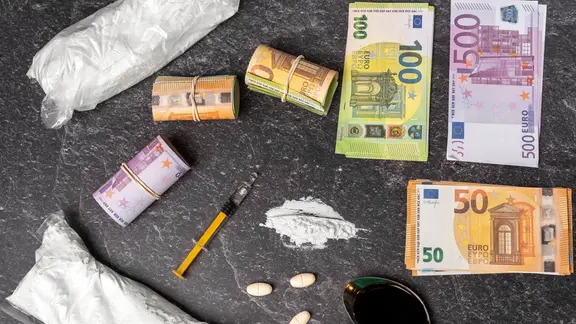 Drogen, Spritze, Tabletten und Geldscheine liegen nebeneinander und zeigen den illegalen Drogenhandel. | picture alliance / CHROMORANGE | MICHAEL BIHLMAYER Drogen, Spritze, Tabletten und Geldscheine liegen nebeneinander und zeigen den illegalen Drogenhandel.