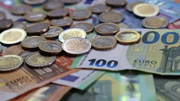 Mehrere Münzen und Euro-Scheinen liegen ausgebreitet auf einem Tisch.
