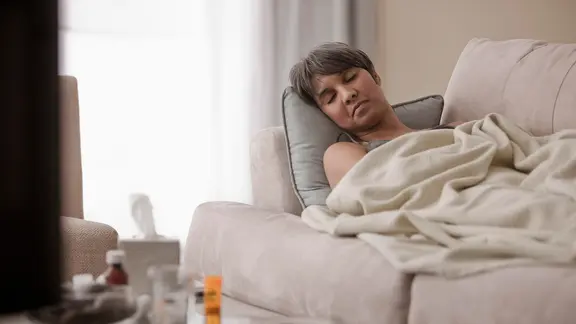 Eine Frau liegt im Bett. Sie sieht erschöpft aus. | picture alliance / Bildagentur-online , Blend Images/John Fedele Eine Frau liegt im Bett. Sie sieht erschöpft aus.