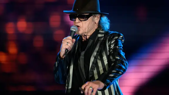 Sachsen, Dresden: Udo Lindenberg singt beim Konzert der neuen Tournee «Udopium Live 2022» im Rudolf-Harbig-Stadion. (zu dpa: «Unicef bringt Antikriegslied von Udo Lindenberg neu heraus») Foto: Robert Michael/dpa +++ dpa-Bildfunk +++ | picture alliance/dpa | Robert Michael Udo Lindenberg singt in ein Mikrofon.