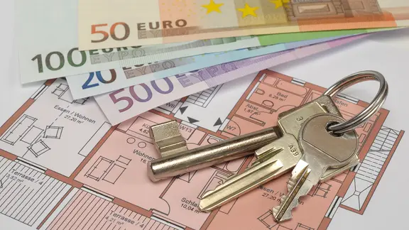 Auf einem Grundriss einer Wohnung liegen Geldscheine und Schlüssel.