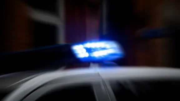 Ein Blaulicht leuchtet an einem Streifenwagen bei Dämmerung.