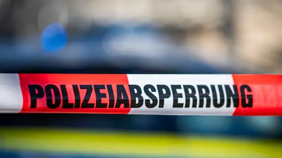 Auf einem rot-weiß-gestreiftem Band steht "Polizeiabsprerrung. | David Inderlied/dpa Auf einem rot-weiß-gestreiftem Band steht "Polizeiabsprerrung.