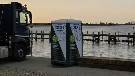 Im Hafen von Poel steht ein Dixie-Klo. Es besteht, laut Aufschrift, zum Teil aus recycelten Fischernetzen. | Christoph Woest Im Hafen von Poel steht ein Dixie-Klo. Es besteht, laut Aufschrift, zum Teil aus recycelten Fischernetzen.