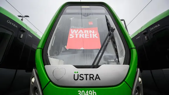 Ein Plakat "Warnstreik" klebt in den Frontscheibe einer Stadtbahn der Hannoverschen Verkehrsbetriebe Üstra auf dem Betriebshof Glocksee. | picture alliance/dpa, Julian Stratenschulte Ein Plakat "Warnstreik" klebt in den Frontscheibe einer Stadtbahn der Hannoverschen Verkehrsbetriebe Üstra auf dem Betriebshof Glocksee.