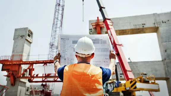 Ein Bauarbeiter schaut sich einen Bauplan auf einer Baustelle an. | fotolia, Rawpixel.com Ein Bauarbeiter schaut sich einen Bauplan auf einer Baustelle an.