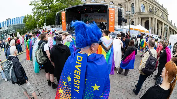 Teilnehmer stehen beim Christopher Street Day (CSD) 2025 auf dem Opernplatz in der Innenstadt von Hannover. | picture alliance/dpa, Michael Matthey Teilnehmer stehen beim Christopher Street Day (CSD) 2025 auf dem Opernplatz in der Innenstadt von Hannover.