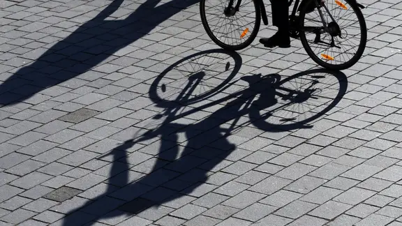 Der Schatten eines Radfahrers und einer Passantin auf Straßenpflaster | picture alliance, dpa, Wolfgang Kumm Der Schatten eines Radfahrers und einer Passantin auf Straßenpflaster