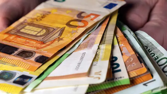 In zwei Händen liegt eine große Menge Bargeld.