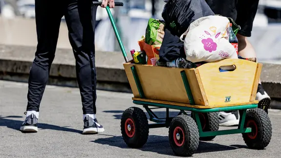 Eine Person zieht einen Bollerwagen über die Kiellinie.