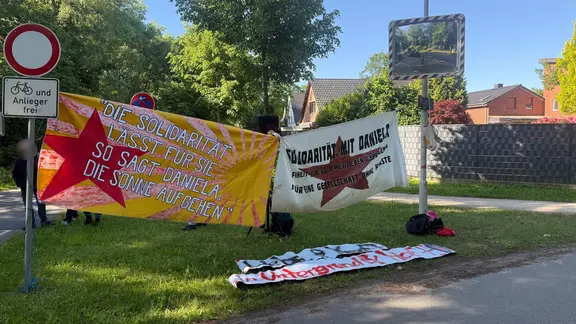 Anhänger von Daniela Klette demonstrieren vor dem Gerichtssaal. | NDR, Maja Chiara Hülcher Vor dem provisorischen Gerichtssaal in Verden halten Demonstrierende Plakate mit der Aufschrift "Solidarität mit Daniela Klette"