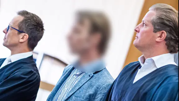 Der Angeklagte Christian B. steht zwischen seinen Verteidigern im Gerichtssaal in Braunschweig.