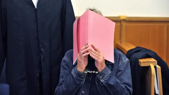 Der Angeklagte Martin N. verdeckt sein Gesicht mit einer Aktenmappe. | picture alliance / dpa, Carmen Jaspersen Der Angeklagte Martin N. verdeckt sein Gesicht mit einer Aktenmappe.