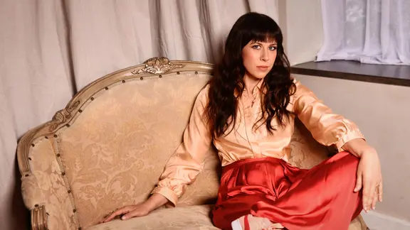 Missy Mazzoli posiert auf einem Sofa.