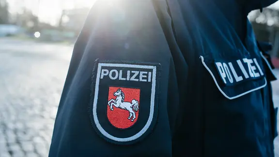 Auf dem Jackenärmel einer blauen Polizeiuniform ist das niedersächsische Wappen aufgenäht. | NDR, Julius Matuschik Auf dem Jackenärmel einer blauen Polizeiuniform ist das niedersächsische Wappen aufgenäht.