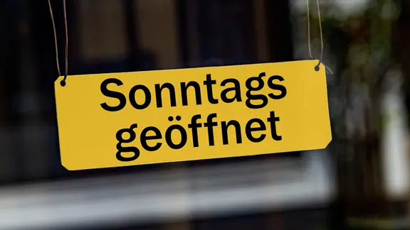 Ein gelbes Schild mit der Aufschrift "Sonntags geöffnet".