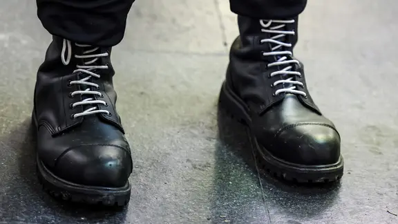 Ein Teilnehmer einer rechtsextremen Kundgebung trägt schwarze Springerstiefel mit weißen Schnürriemen.