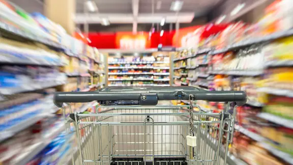 Ein leerer Einkaufswagen zwischen Regalreihen im Supermarkt mit Bewegungsunschärfe. (Themenbild) | picture alliance, Klaus Ohlenschläger Ein leerer Einkaufswagen zwischen Regalreihen im Supermarkt mit Bewegungsunschärfe. (Themenbild)