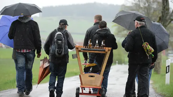 Bei regnerischem Wetter gehen Menschen mit Bollerwagen und Regenschirmen einen Straße entlang. | picture alliance / dpa | Patrick Seeger Bei regnerischem Wetter gehen Menschen mit Bollerwagen und Regenschirmen einen Straße entlang.