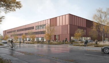 Die Visualisierung zeigt das Labor- und Bürogebäude für die Bundesanstalt für Materialforschung und -prüfung (BAM) in rostroter Farbe und eckiger Form.