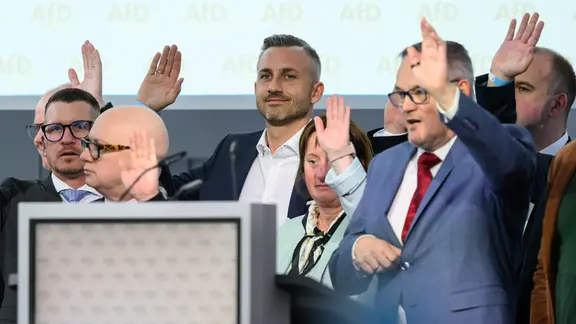 Martin Reichardt (vorn), Landesvorsitzender der AfD Sachsen-Anhalt, und Ulrich Siegmund (3.v.r.), Spitzenkandidat für die Landtagswahl 2026, heben ihre Hände während der Abstimmung über das Regierungsprogramm auf dem Landesparteitag der AfD Sachsen-Anhalt in Magdeburg. | picture alliance/dpa | Hendrik Schmidt Martin Reichardt (vorn), Landesvorsitzender der AfD Sachsen-Anhalt, und Ulrich Siegmund (3.v.r.), Spitzenkandidat für die Landtagswahl 2026, heben ihre Hände während der Abstimmung über das Regierungsprogramm auf dem Landesparteitag der AfD Sachsen-Anhalt in Magdeburg.