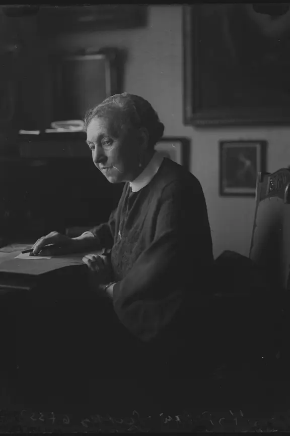 Porträt von Hedwig Platky (1862–1941), die jüdische Witwe eines Rauchwarenhändlers und Kunstsammlers, in ihrer Wohnung. | Stadtgeschichtliches Museum Leipzig/Abram Mittelmann Hedwig Platky, eine alte Dame in Trauerkleidung und mit strengem Dutt am Tisch in ihrer Wohnung. Foto: Atelier Mittelmann, vor 1933.