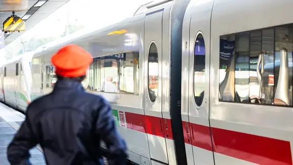 Ein Mitarbeiter der Deutschen Bahn (DB) steht neben einem ICE-Zug an einem Gleis im Hauptbahnhof Hannover. | picture alliance/dpa/Michael Matthey, Michael Matthey Ein Mitarbeiter der Deutschen Bahn (DB) steht neben einem ICE-Zug an einem Gleis im Hauptbahnhof Hannover.