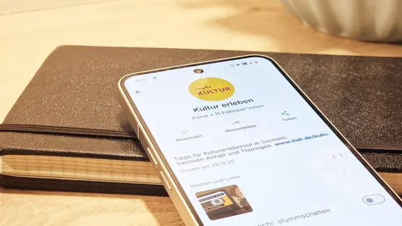 Smartphone mit geöffnetem WhatsApp-Kanal "Kultur erleben" auf einem Notizbuch | MDR/Mandy Schalast-Peitz Smartphone mit geöffnetem WhatsApp-Kanal "Kultur erleben" auf einem Notizbuch