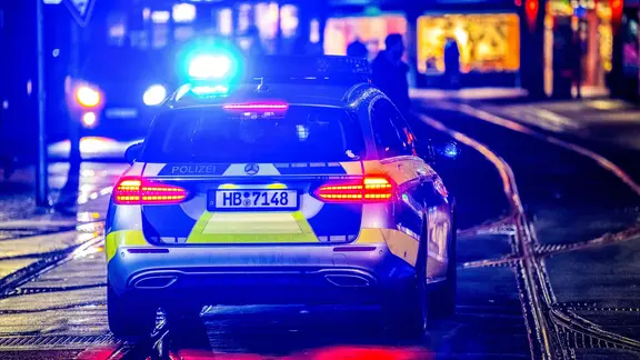 Ein Polizeiwagen fährt bei Nacht mit eingeschaltetem Blaulicht durch einen Straße in Bremen. | picture alliance/dpa , Sina Schuldt Ein Polizeiwagen fährt bei Nacht mit eingeschaltetem Blaulicht durch einen Straße in Bremen.