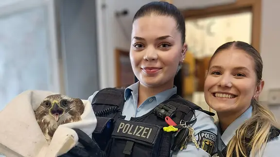 Flugunfähiger Greifvogel in Gleis 6a - kein gewöhnlicher Einsatz für die Bundespolizei im Kieler Hauptbahnhof. Die Bilanz der Rettung: Verdacht auf Flügelbruch und ein Foto mit Seltenheitswert. | Bundespolizeiinspektion Kiel Zwei Polizistinnen mit einem gefangenen Bussard