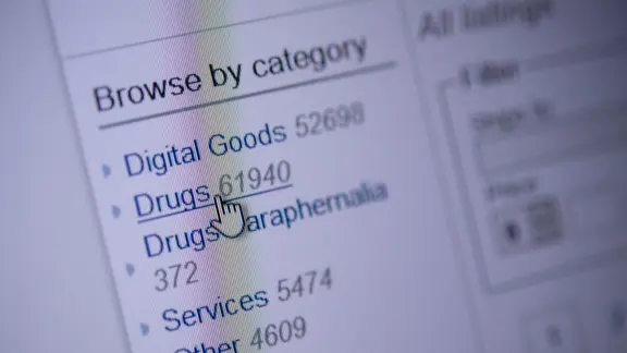 Ein Mauszeiger deutet auf der Homepage eines Darknet-Shops auf den Menüpunkt «Drugs» (zu deutsch: Drogen). | picture alliance/dpa | Sebastian Gollnow Ein Mauszeiger deutet auf der Homepage eines Darknet-Shops auf den Menüpunkt «Drugs» (zu deutsch: Drogen).
