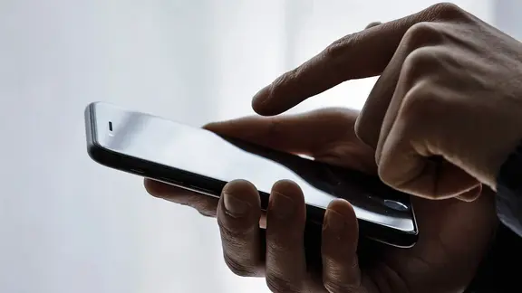 Eine Person hält ein Smartphone in der Hand. | picture alliance / photothek | Thomas Trutschel, Thomas Trutschel Eine Person hält ein Smartphone in der Hand.