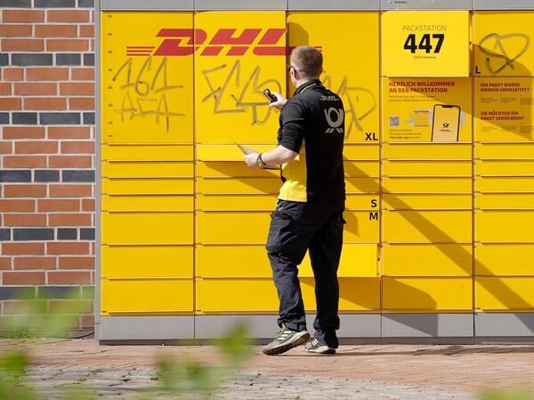 ARCHIV - 15.04.2026, Hamburg: Ein DHL-Mitarbeiter schließt ein Fach einer Packstation im Stadtteil Harburg. (zu dpa: «Post will Mitarbeiter mit «Cool-Boxen» gegen Hitze schützen») Foto: Marcus Brandt/dpa +++ dpa-Bildfunk +++