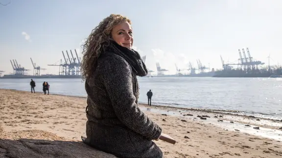 Eine Frau sitzt in Hamburg am Elbstrand und geniesst das gute Wetter | picture alliance / dpa Themendienst, Christin Klose Eine Frau sitzt in Hamburg am Elbstrand und geniesst das gute Wetter