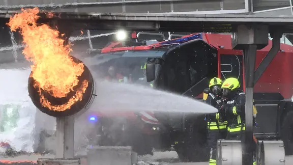 Feuerwehrkräfte löschen bei der Messe Interschutz einen simulierten Brand. | picture alliance/dpa, Julian Stratenschulte Feuerwehrkräfte löschen bei der Messe Interschutz einen simulierten Brand.