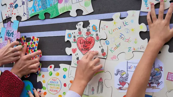 Kinder gestalten ihren Tag mit: Sie wirken aktiv an der Vorbereitung des Kinderrechte-Gipfels in Kiel mit. | IMAGO / epd An einer Wand werden bemalte Puzzleteile von Kindern aufgehängt.