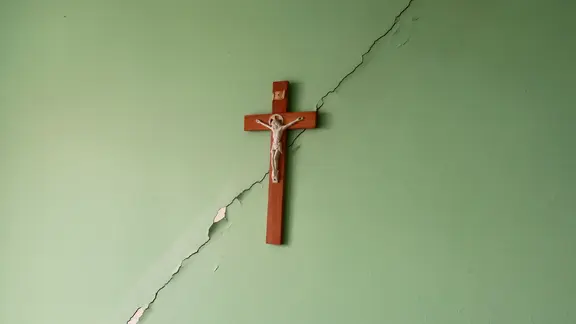 Ein Kirchenkreuz hängt an einer brüchigen Wand. | NDR Ein Kirchenkreuz hängt an einer brüchigen Wand.